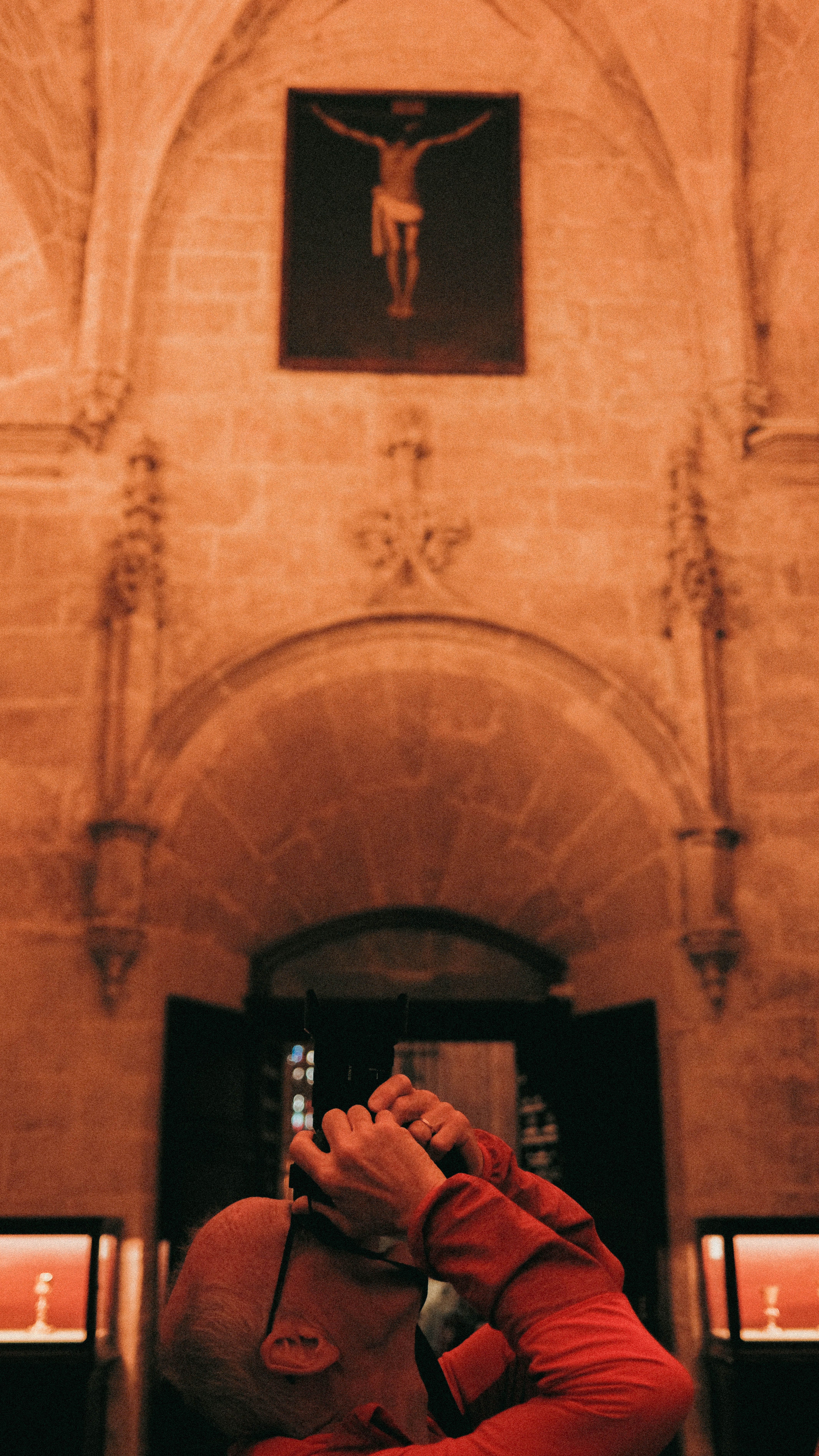 Une personne photographie une œuvre d'art dans un édifice patrimonial.